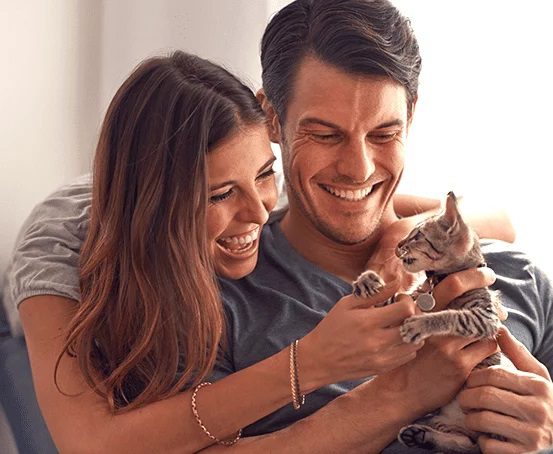 a man and woman playing with a kitten